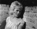 Wendy Richard sitting in front of a brick wall.  July 1962 publicity photo.