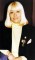 Wendy Richard in a dark suit, wearing golden heart brooch pins